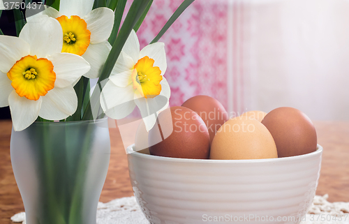 Image of Easter eggs in a ceramic vase and flowers daffodils.