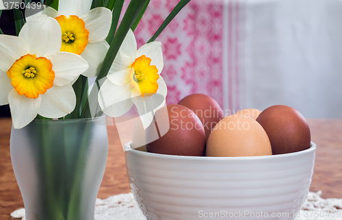 Image of Easter eggs in a ceramic vase and flowers daffodils.