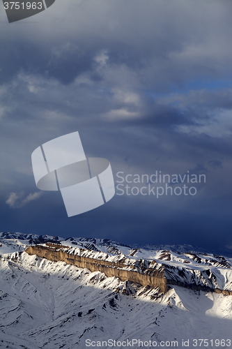Image of Sunlight winter mountains and storm clouds at evening.