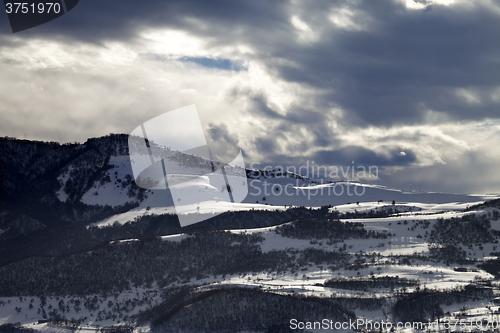 Image of Village in winter mountains and storm clouds at evening