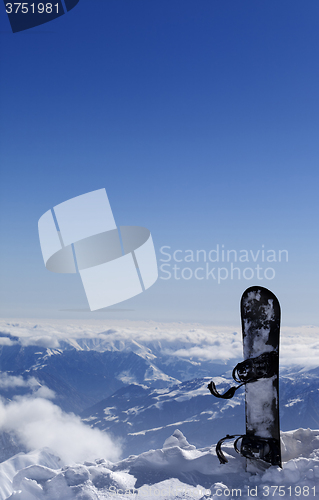 Image of Snowboard in snow on off-piste slope at sun day