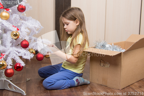 Image of Sad girl removes a Christmas tree with toys