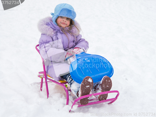 Image of Joyful girl sitting on a sled