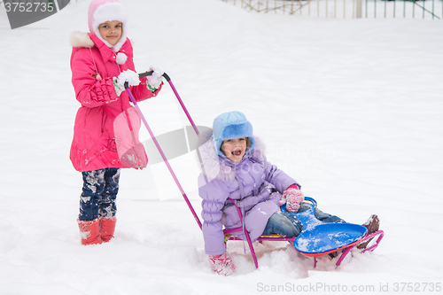 Image of Two girls ride each other on a sled