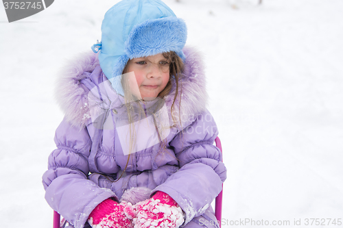 Image of Tired girl sitting on a sled