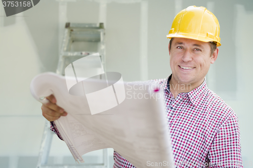 Image of Contractor Holding Blueprints Inside Home Construction Site