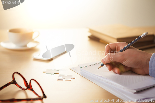 Image of The male hands with a pencil and the cup