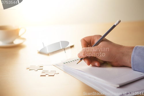 Image of The male hands with a pencil and the cup