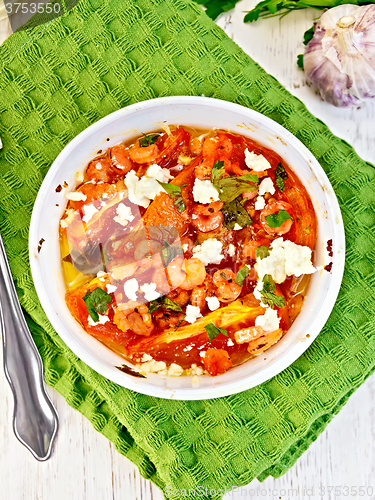 Image of Shrimp and tomatoes with feta in white bowl on napkin top