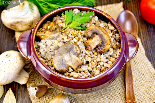 Image of Buckwheat with champignons in clay bowl on table