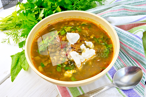 Image of Soup lentil with spinach and cheese in yellow bowl on board