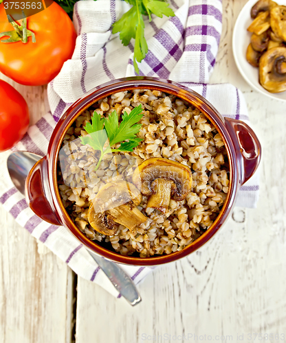 Image of Buckwheat with champignons in clay bowl on board top