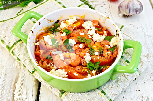 Image of Shrimp and tomatoes with feta in green pan on board