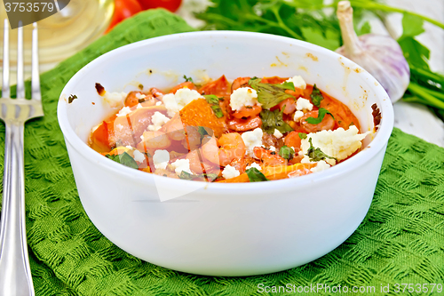 Image of Shrimp and tomatoes with feta in white bowl on board