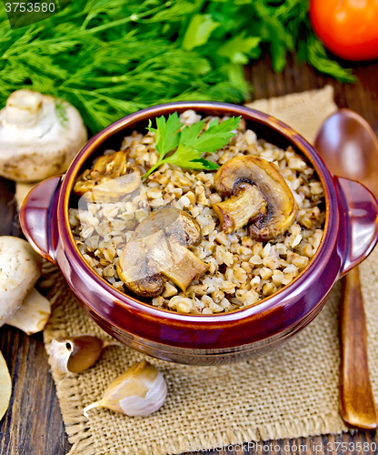Image of Buckwheat with champignons in clay bowl on sacking