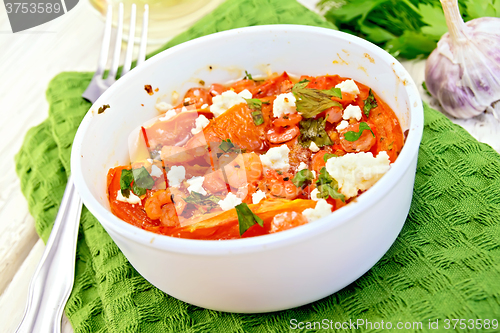 Image of Shrimp and tomatoes with feta in white bowl on light board