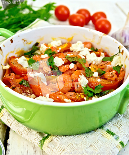Image of Shrimp and tomatoes with feta in green pan on napkin