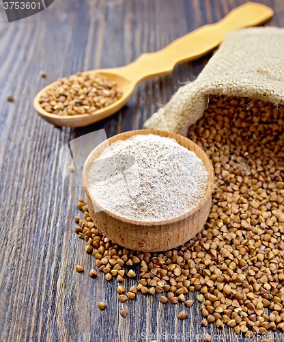Image of Flour buckwheat in bowl and spoon with cereals on dark board