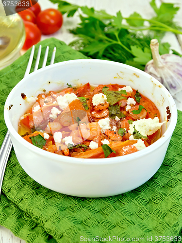 Image of Shrimp and tomatoes with feta in white bowl on green napkin