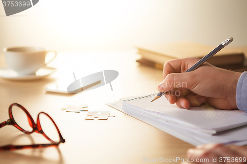 Image of The male hands with a pencil and the cup