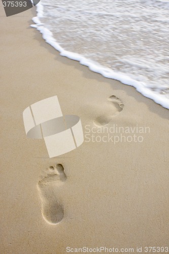 Image of Footprints on beach and wave