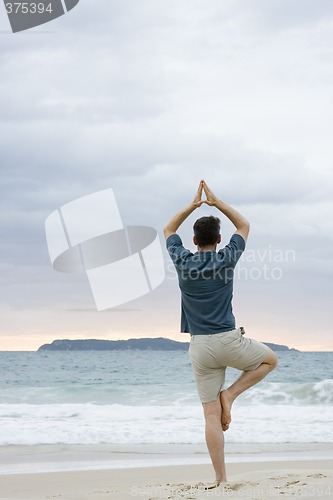 Image of Man doing yoga on beach