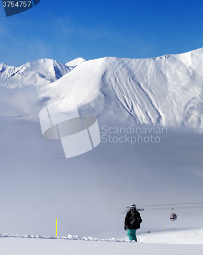 Image of Snowboarder on off-piste slope and mountains in mist