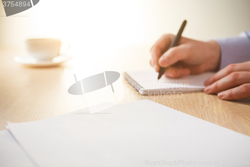 Image of The male hand with a pen and the cup