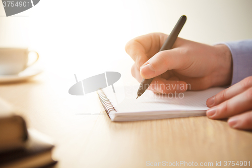 Image of The male hand with a pen and the cup