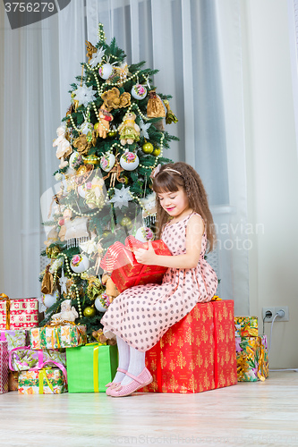 Image of Happy little girl with christmas present smiling