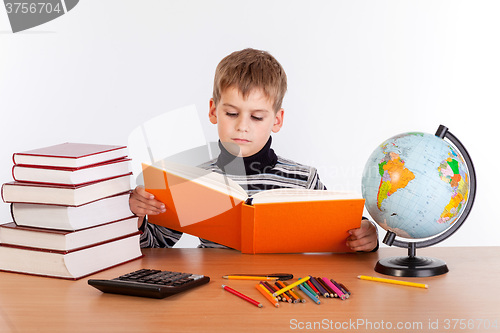 Image of Cute schoolboy is reading a book