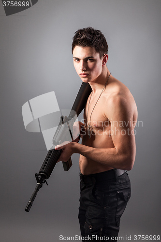 Image of Handsome bare-chested soldier is holding a rifle