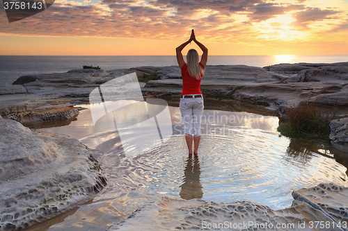 Image of Woman yoga meditation by the ocean sunrise