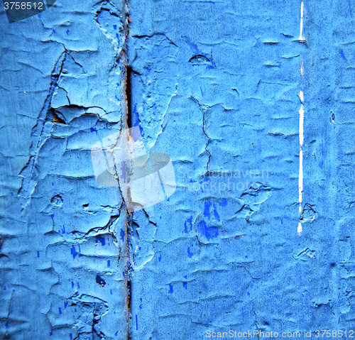 Image of dirty stripped paint in the blue wood door and rusty nail