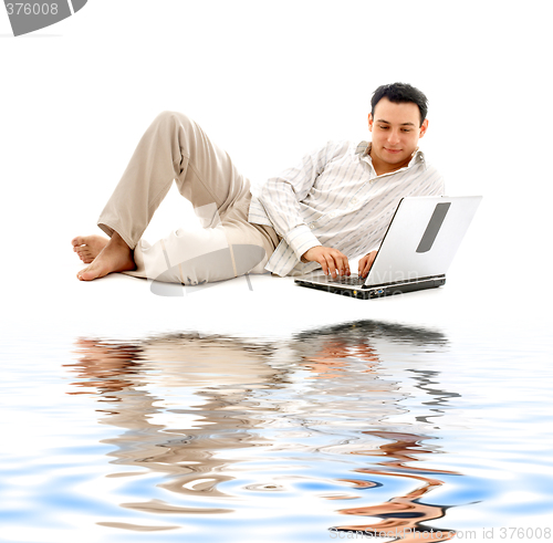 Image of relaxed man with laptop on white sand