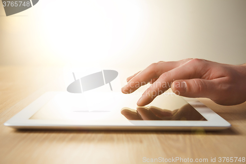 Image of The tablet with the hand on wooden table