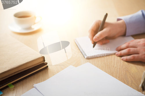 Image of The male hand with a pen and the cup