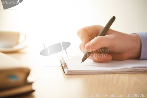 Image of The male hand with a pen and the cup