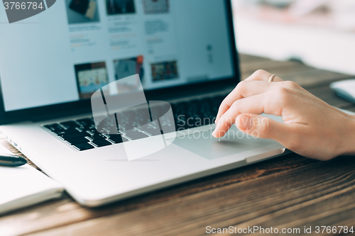 Image of Woman working with laptop placed on wooden desk