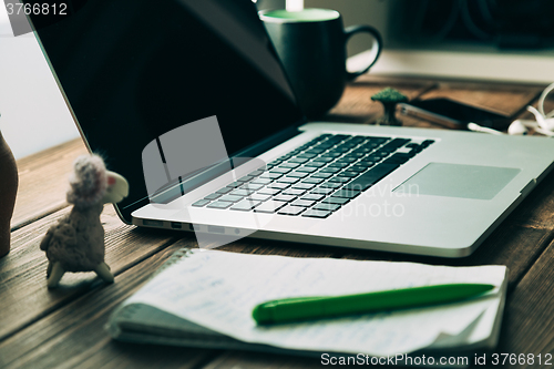 Image of Workplace with open laptop on modern wooden desk 