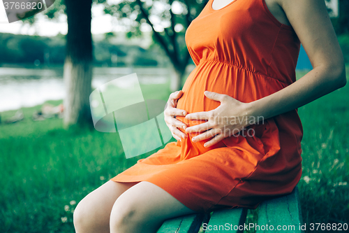 Image of Pregnant woman, holding in hands bouquet of daisy 