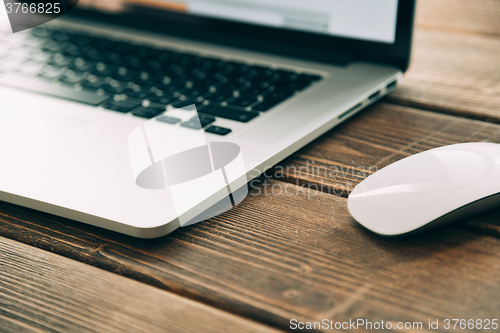 Image of Workplace with open laptop on modern wooden desk 