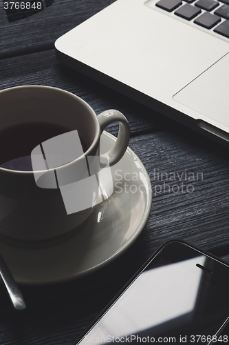Image of Office table with notepad, computer and tea cup