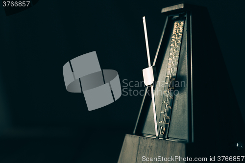 Image of Vintage metronome, on a dark background.