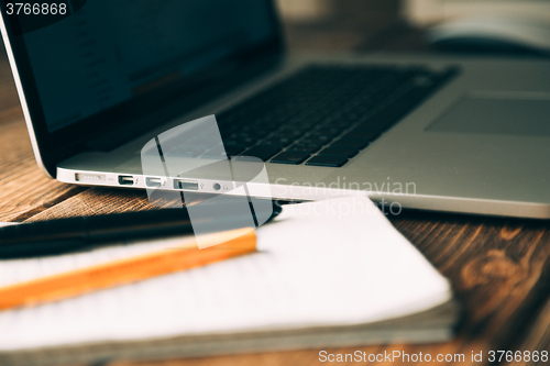 Image of Workplace with open laptop on modern wooden desk 