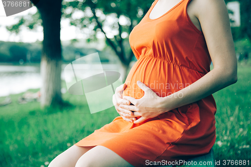 Image of Pregnant woman, holding in hands bouquet of daisy 