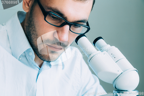 Image of Young male doctor viewing through microscope