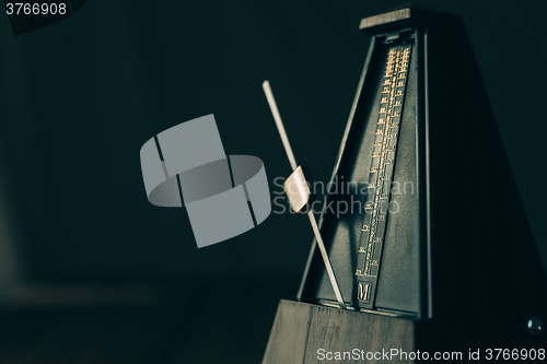 Image of Vintage metronome, on a dark background.