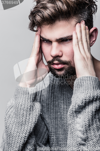 Image of Portrait of a young man in gray pullover. Headache