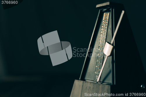 Image of Vintage metronome, on a dark background.